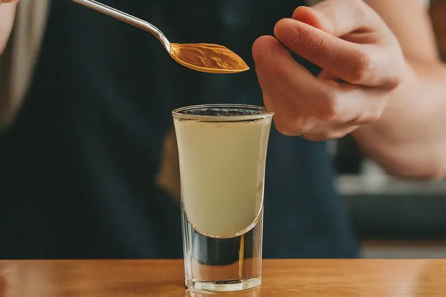 Mixing lemon juice and ground mushrooms in a shot glass for lemon tek preparation