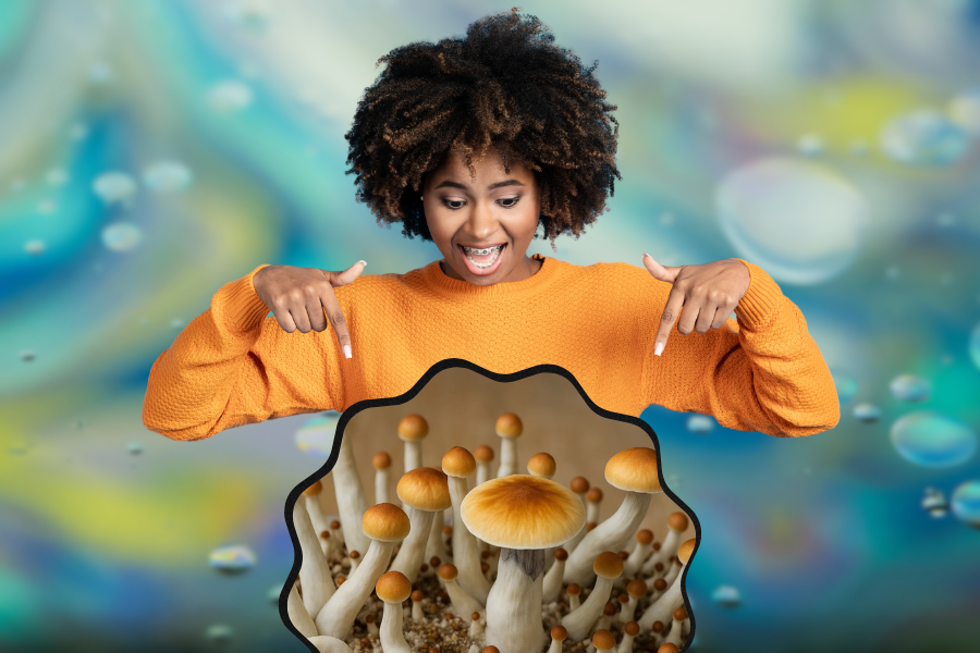 A woman in an orange sweater points excitedly at a cluster of Golden Teacher Mushrooms in front of her, with a blurred, colorful background.