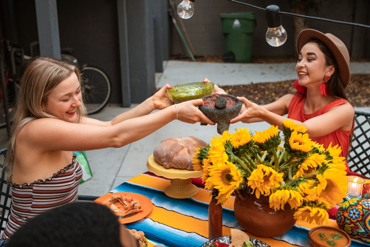 People sharing food around a table during an outdoor gathering. Access to healing, Who gets to heal